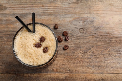 Photo of Glass of tasty refreshing cocktail with coffee beans on wooden background, top view. Space for text