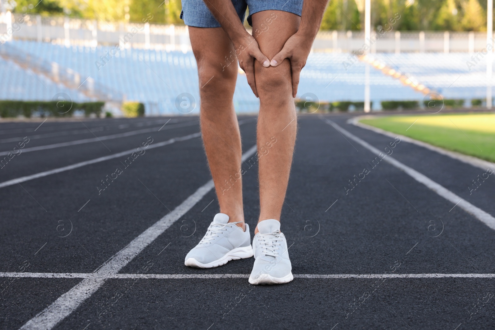 Photo of Man in sportswear having knee problems at stadium, closeup