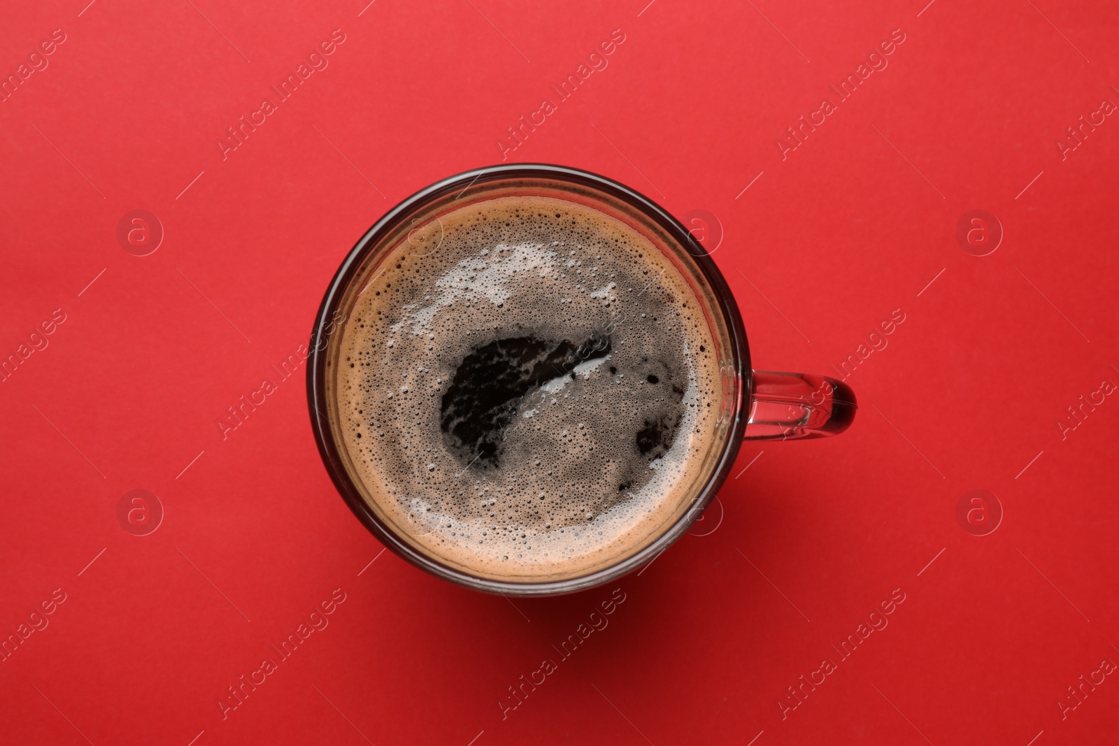 Photo of Fresh coffee in cup on red background, top view