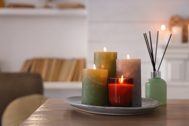 Beautiful burning candles and air freshener on wooden table indoors, space for text