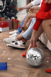 Photo of People sitting on sofa in messy room after New Year party, closeup of legs