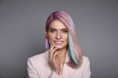 Hair styling. Attractive woman with colorful hair on grey background