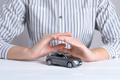 Insurance agent covering toy car on table, closeup