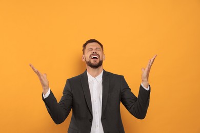 Photo of Aggressive man shouting on orange background. Hate concept