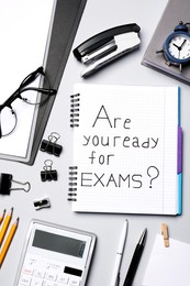 Photo of Notebook with question Are you ready for exams and stationery on grey table, flat lay