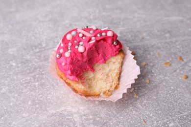 Photo of Failed cupcake with cream on light grey table, closeup. Troubles happen