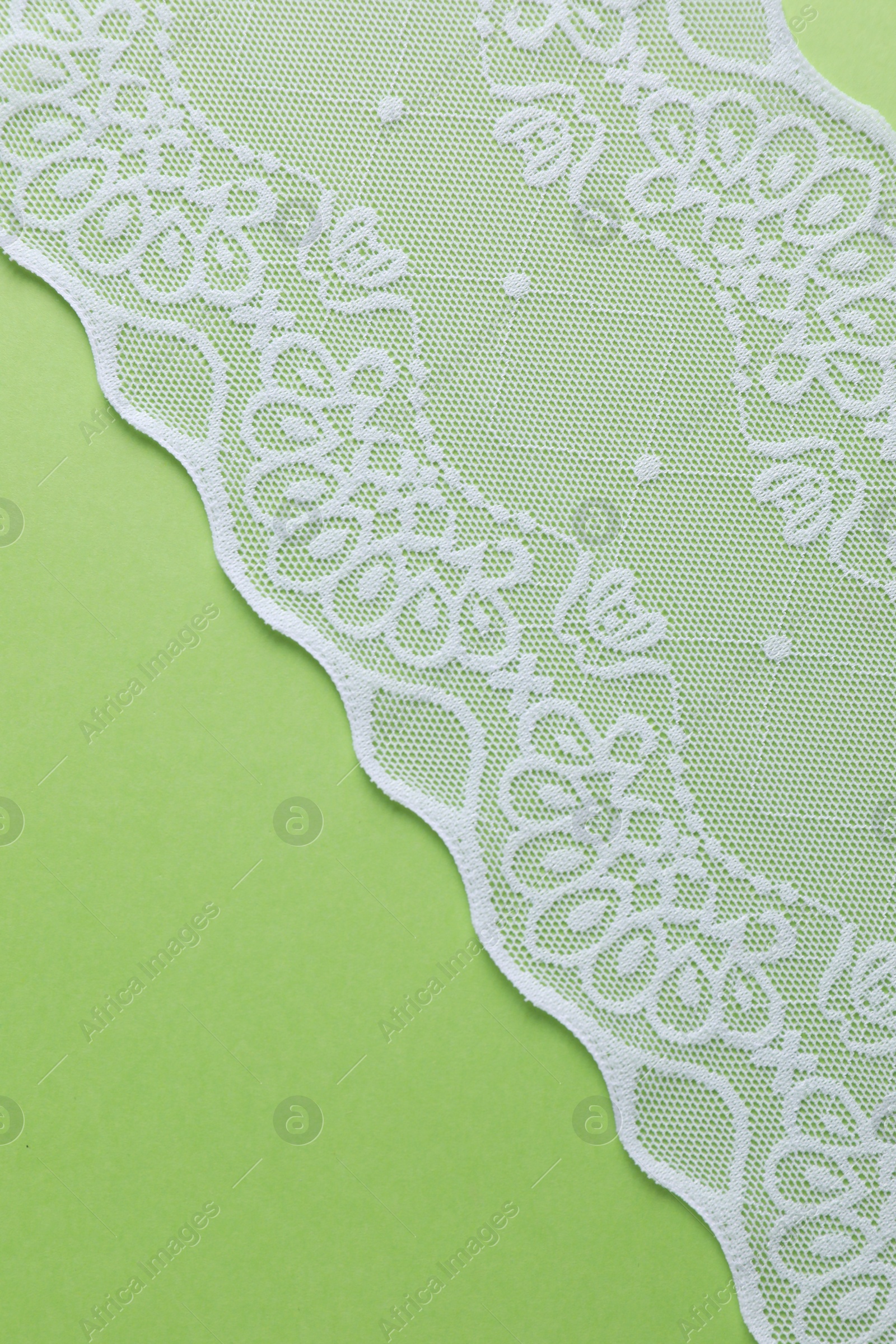 Photo of White lace on green background, top view