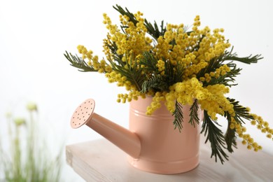 Photo of Beautiful mimosa flowers in watering can on wooden table