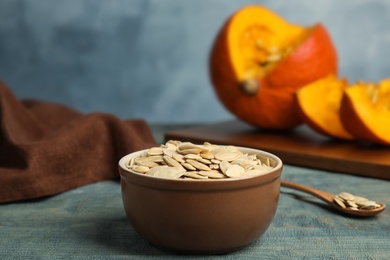 Photo of Bowl of raw pumpkin seeds on blue wooden table