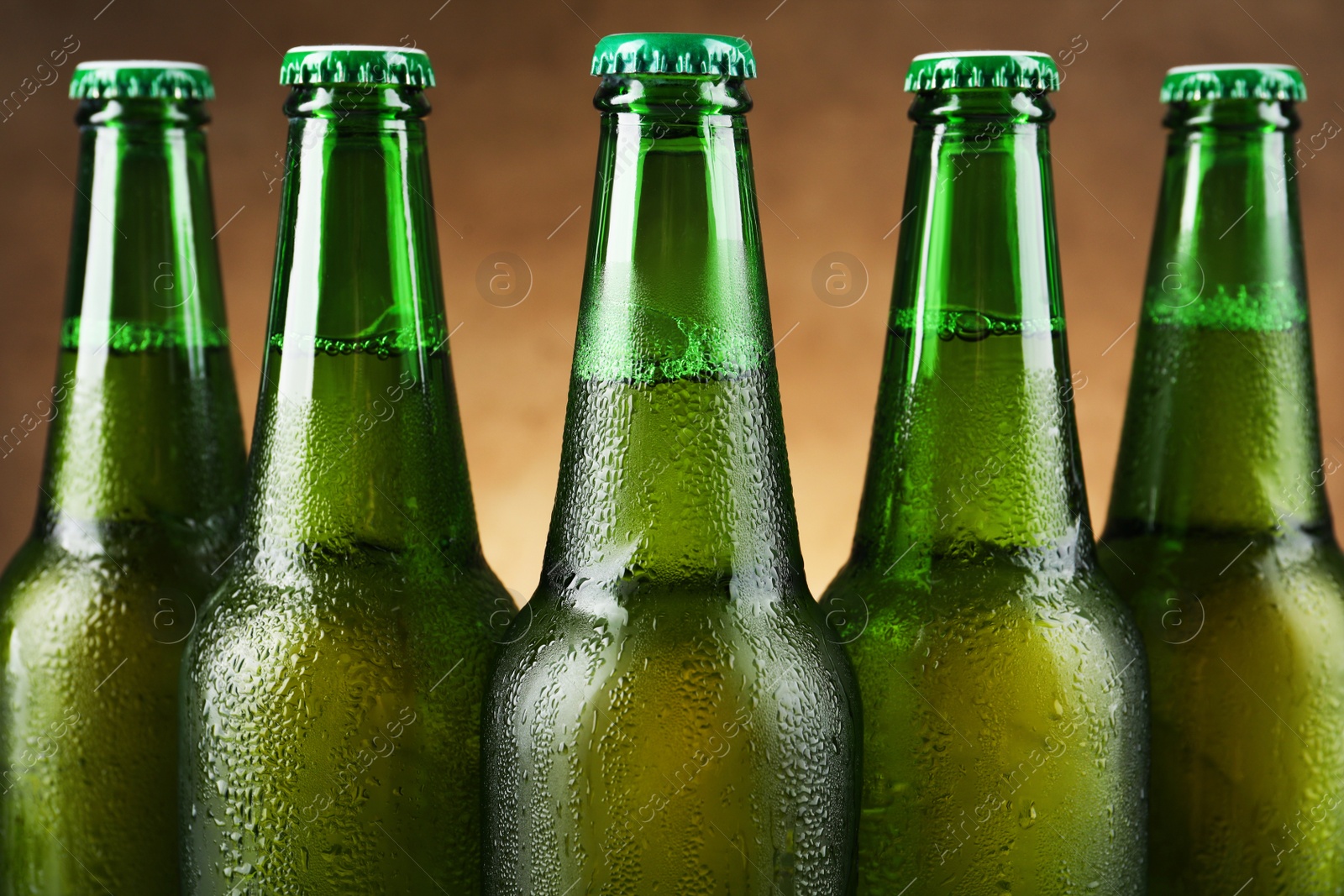 Photo of Many bottles of beer on light brown background, closeup