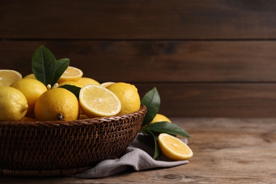 Photo of Many fresh ripe lemons on wooden table, closeup. Space for text