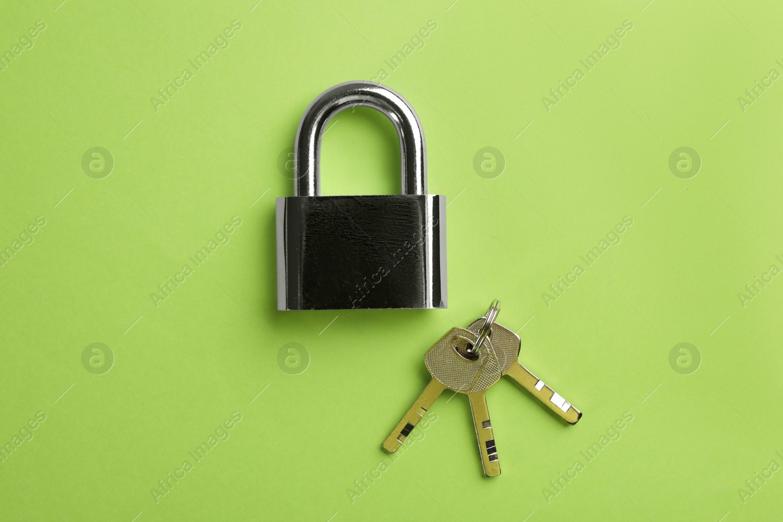 Photo of Modern padlock with keys on green background, flat lay
