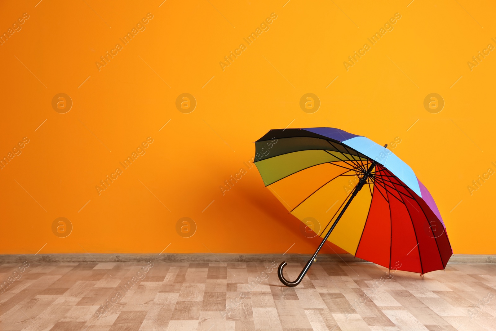 Photo of Beautiful open umbrella on floor near color wall with space for design