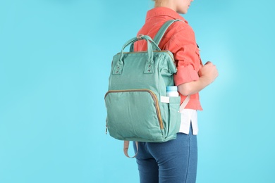 Photo of Woman with maternity backpack for baby accessories on color background, closeup