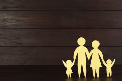 Photo of Paper family figure on wooden table, space for text. Child adoption concept