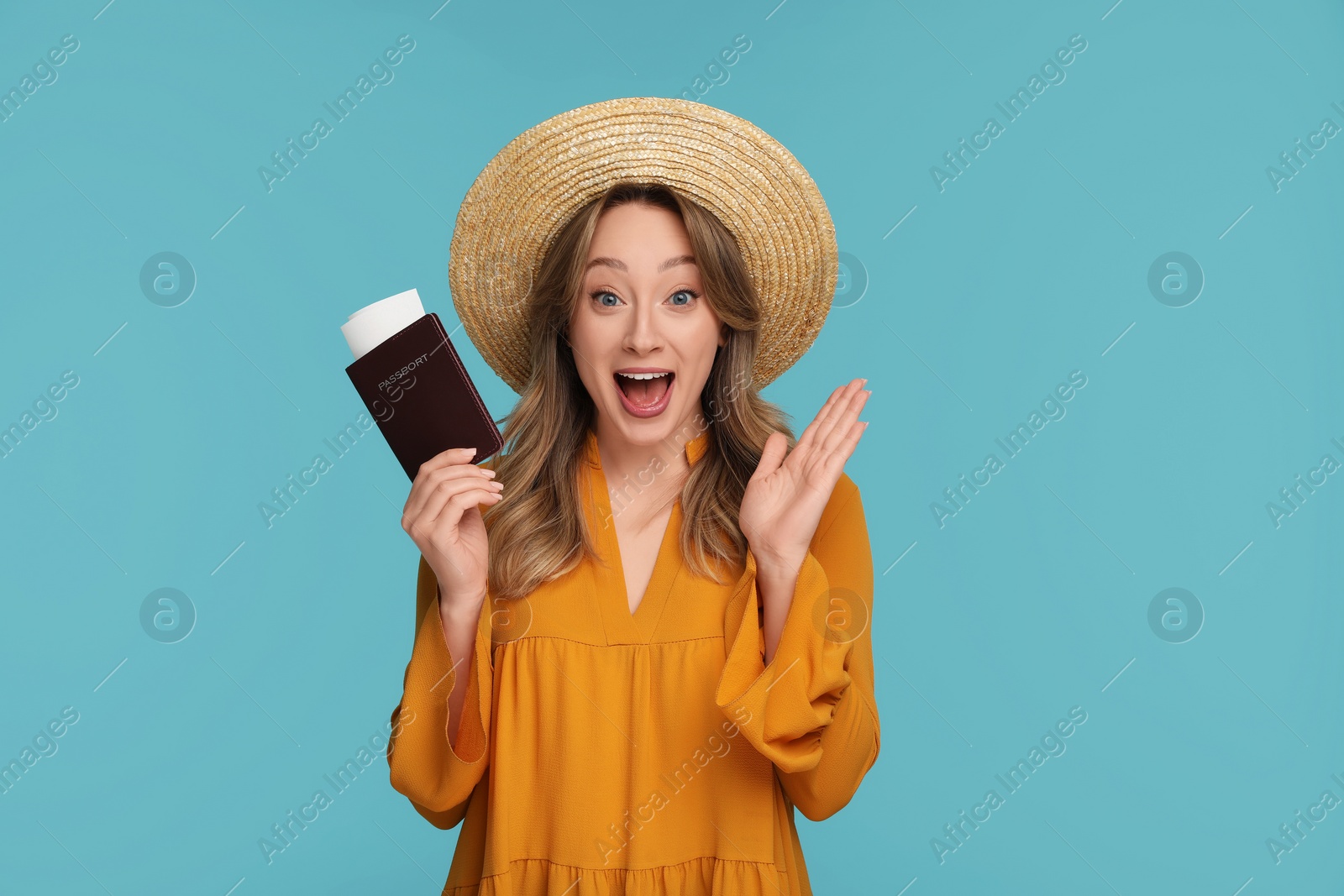 Photo of Emotional young woman with passport, ticket and hat on light blue background