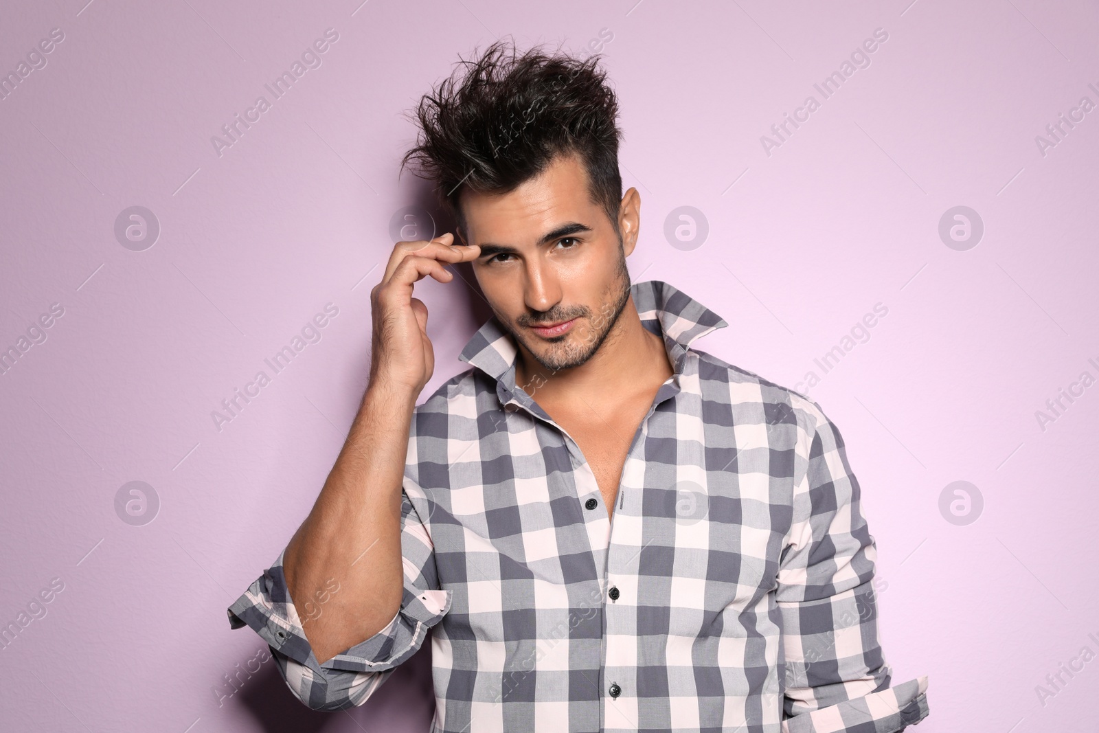 Photo of Young man with trendy hairstyle posing on color background