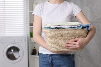 Photo of Woman with basket full of laundry in bathroom, closeup