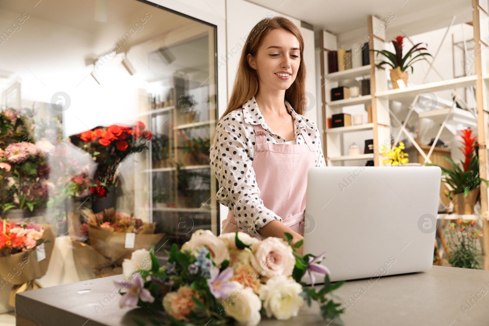 Photo of Professional female florist using laptop at workplace