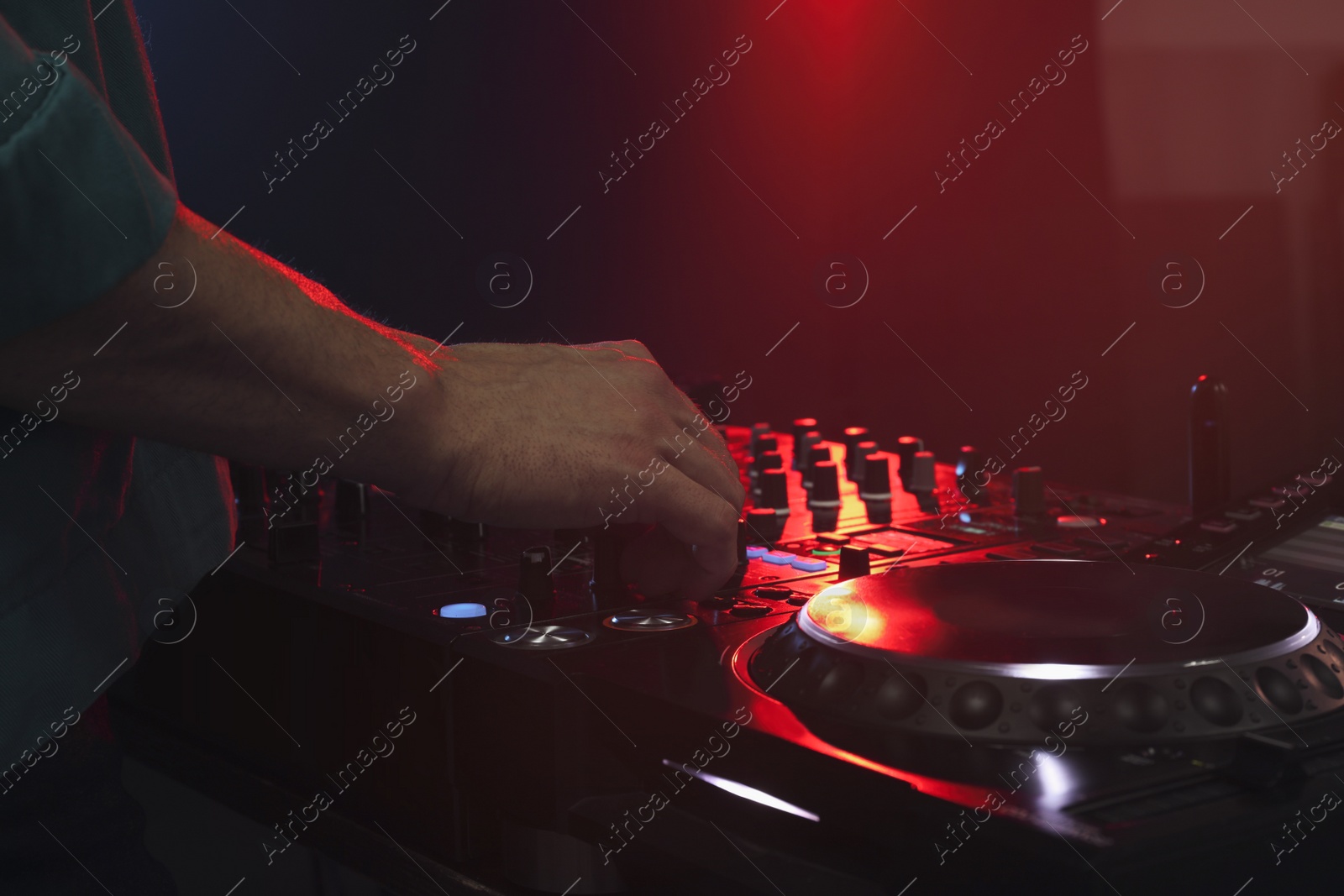 Photo of DJ creating music on modern console mixer in night club, closeup