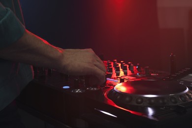 Photo of DJ creating music on modern console mixer in night club, closeup