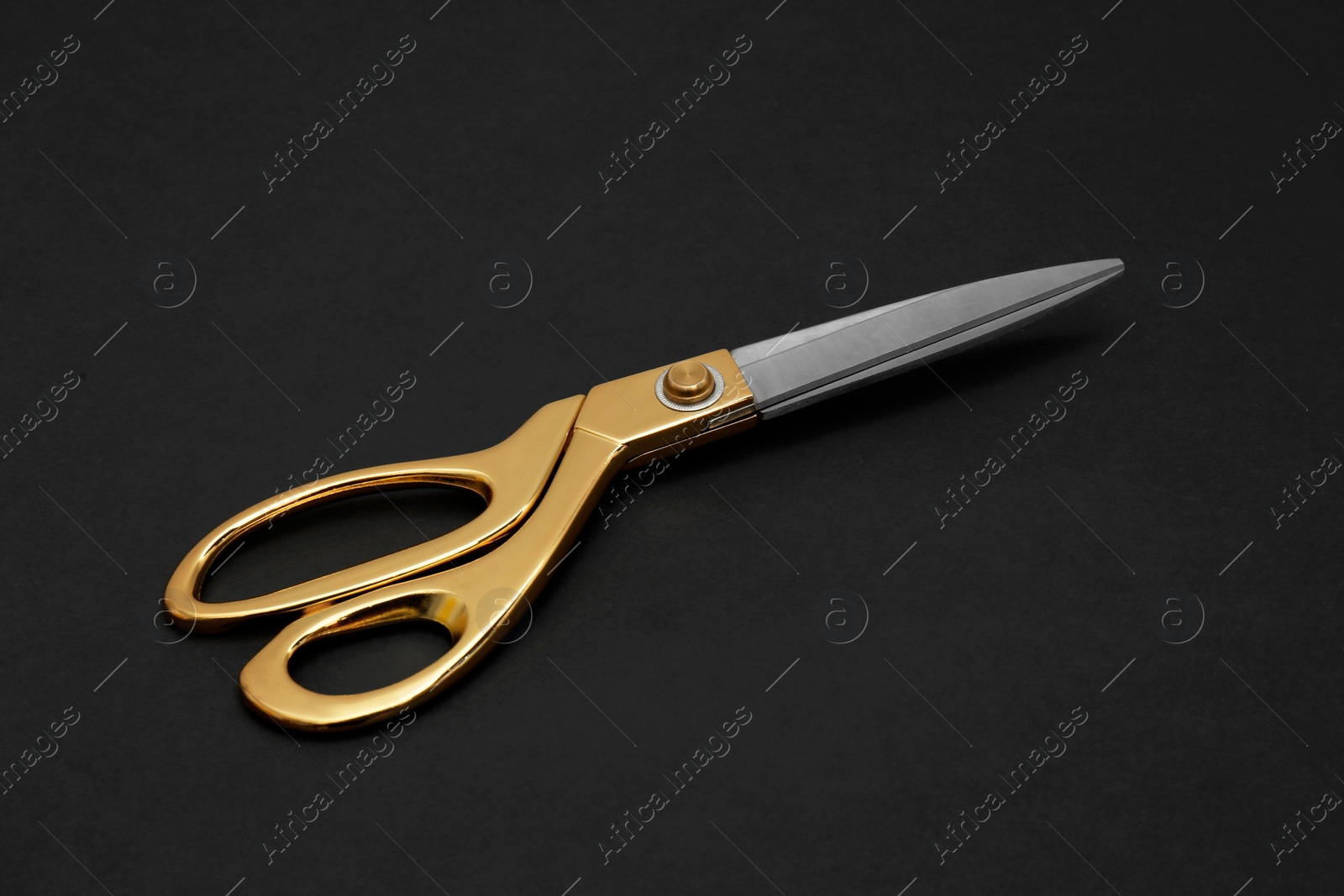 Photo of Stylish gold tailor scissors on black background