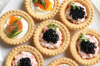 Delicious canapes with salmon and caviar on plate, top view