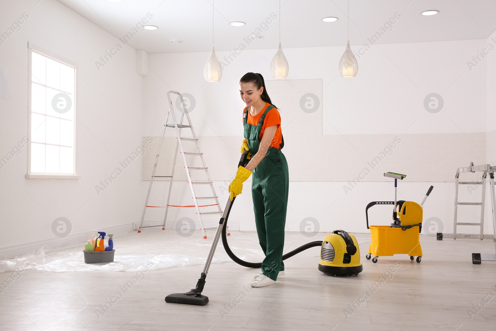 Photo of Professional janitor cleaning room with vacuum after renovation