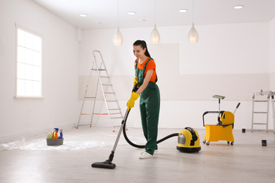 Photo of Professional janitor cleaning room with vacuum after renovation
