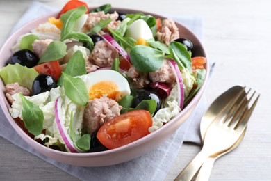 Photo of Bowl of delicious salad with canned tuna and vegetables served on white wooden table, closeup