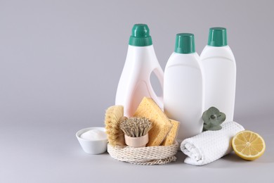 Photo of Bottles of cleaning product, sponges, brushes, lemon and baking soda on light background