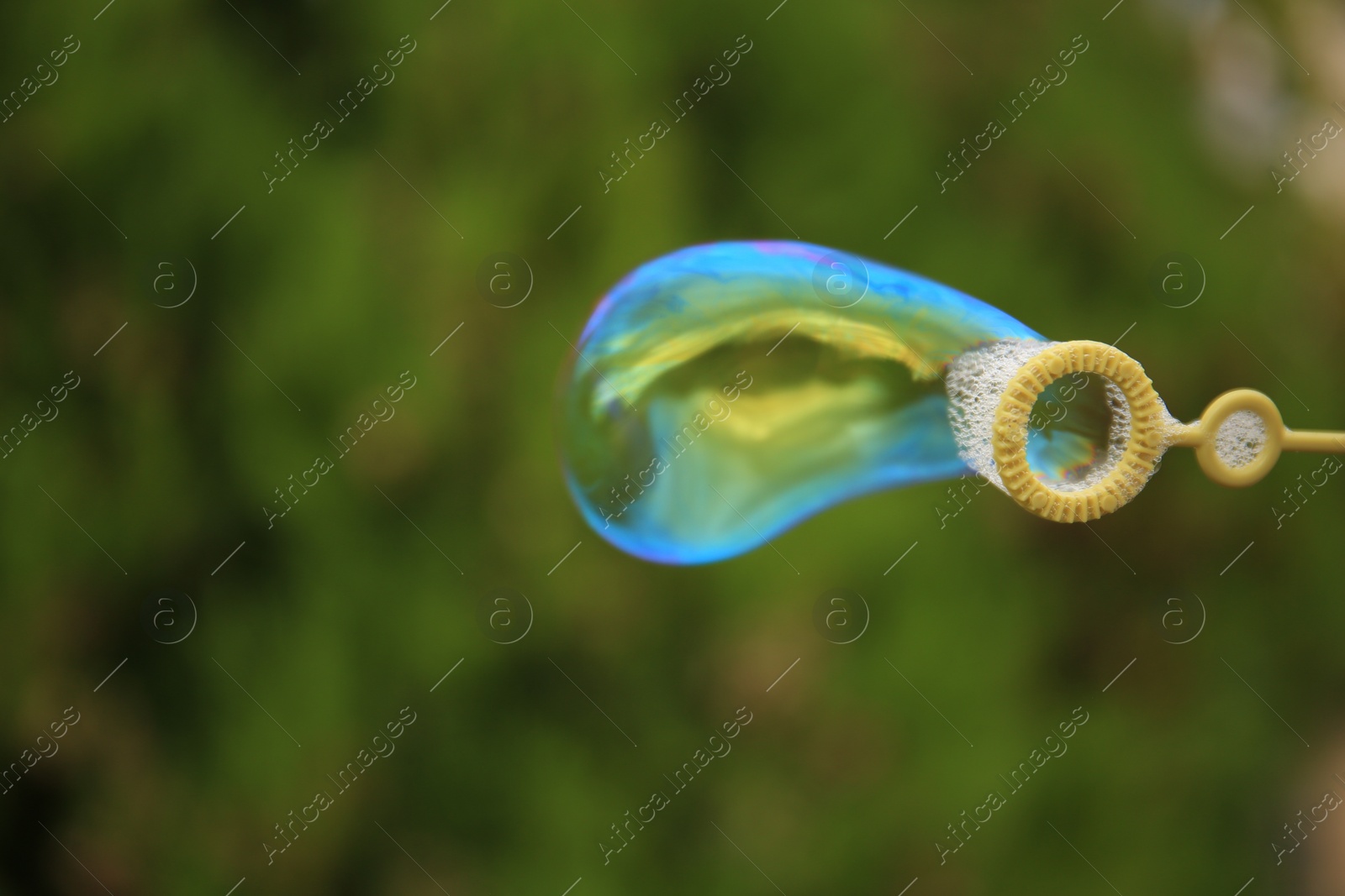 Photo of Blowing beautiful soap bubble outdoors, closeup. Space for text