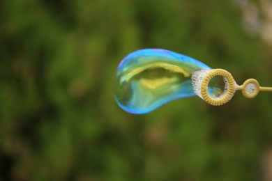 Photo of Blowing beautiful soap bubble outdoors, closeup. Space for text