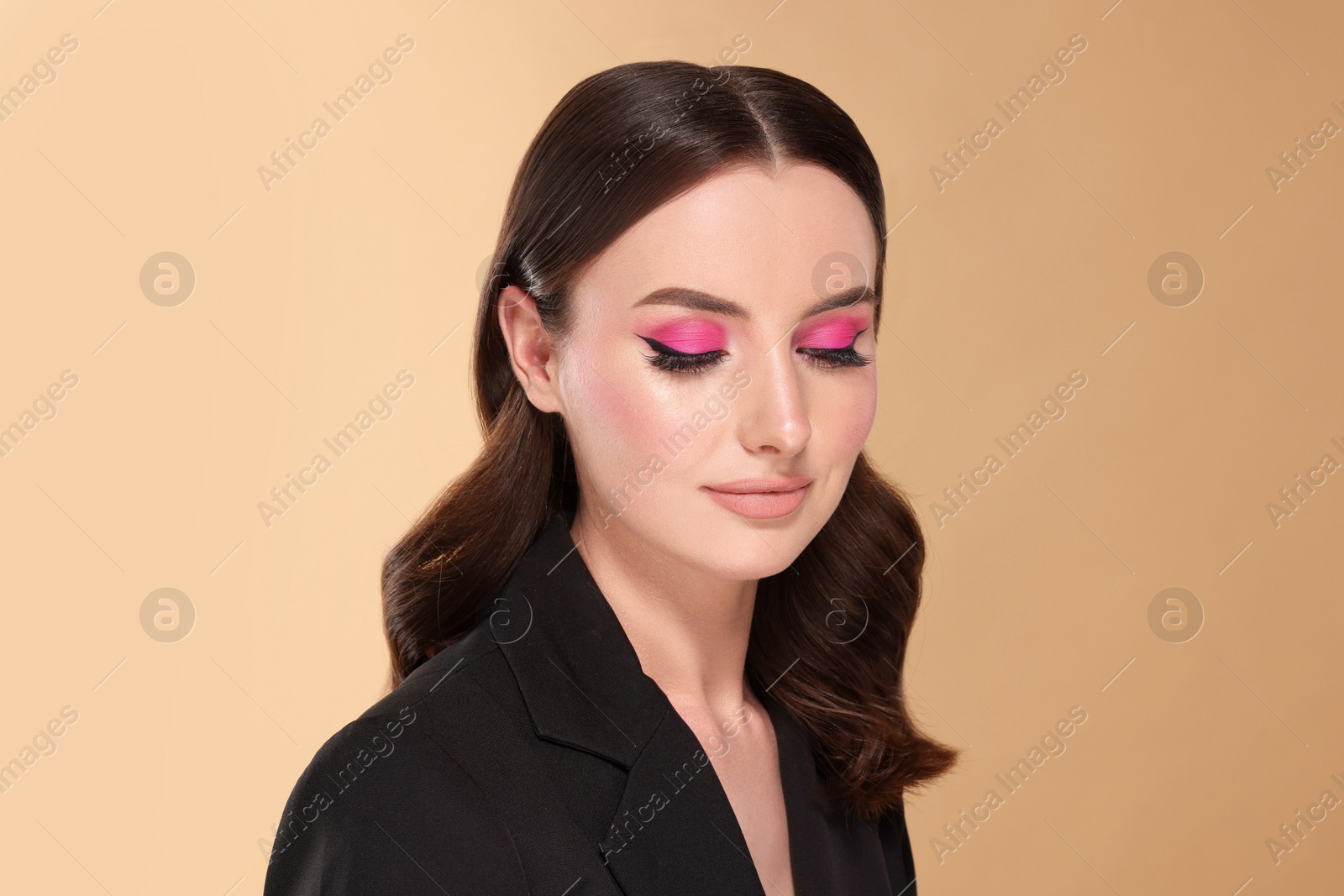 Photo of Portrait of beautiful young woman with makeup and gorgeous hair styling on beige background