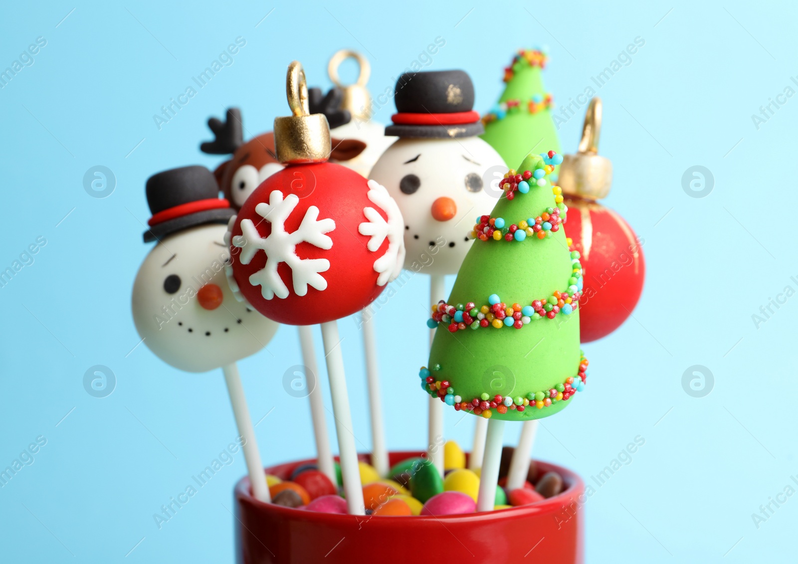 Photo of Delicious Christmas themed cake pops on light blue background, closeup