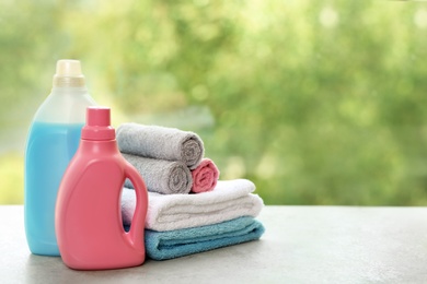 Photo of Stack of clean towels with detergents on table against blurred background. Space for text