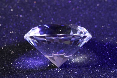 Photo of Beautiful dazzling diamond on violet glitter background, closeup