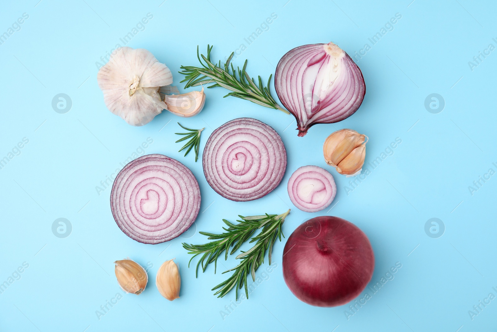 Photo of Fresh red onions, garlic and rosemary on light blue background, flat lay