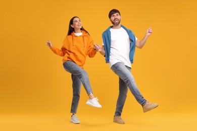 Photo of Happy couple dancing together on orange background