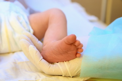 Doctor holding newborn child's foot in hospital, closeup