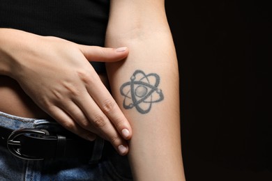 Photo of Woman with tattoo on arm against black background, closeup