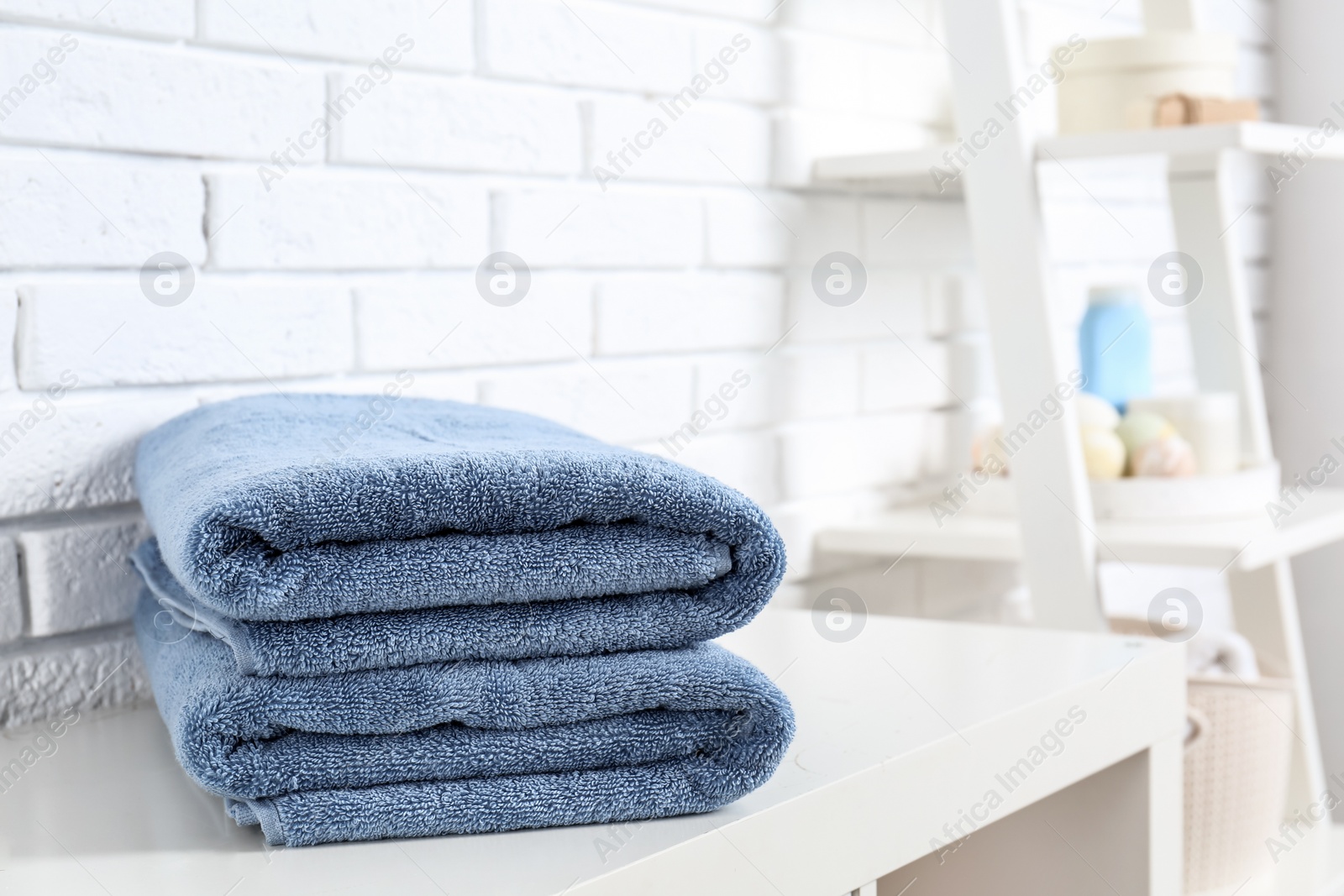 Photo of Stack of fresh towels on table in bathroom. Space for text