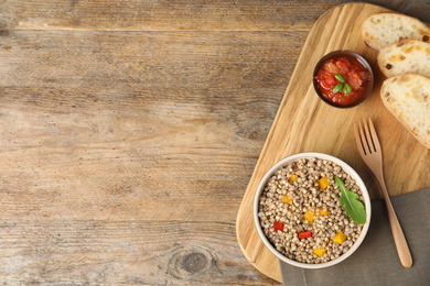 Photo of Tasty buckwheat porridge with salad on wooden table, flat lay. Space for text