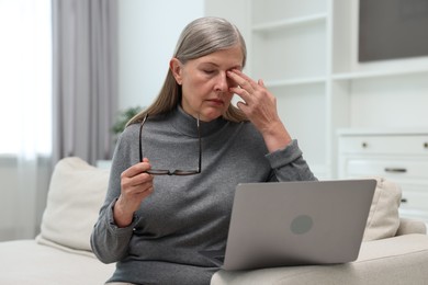 Photo of Overwhelmed woman with laptop sitting on sofa at home