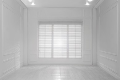 Empty room with white walls, large window and wooden floor