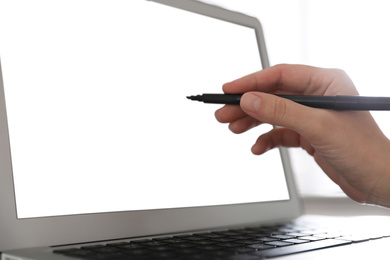 Photo of Woman pointing at modern laptop with blank screen, closeup