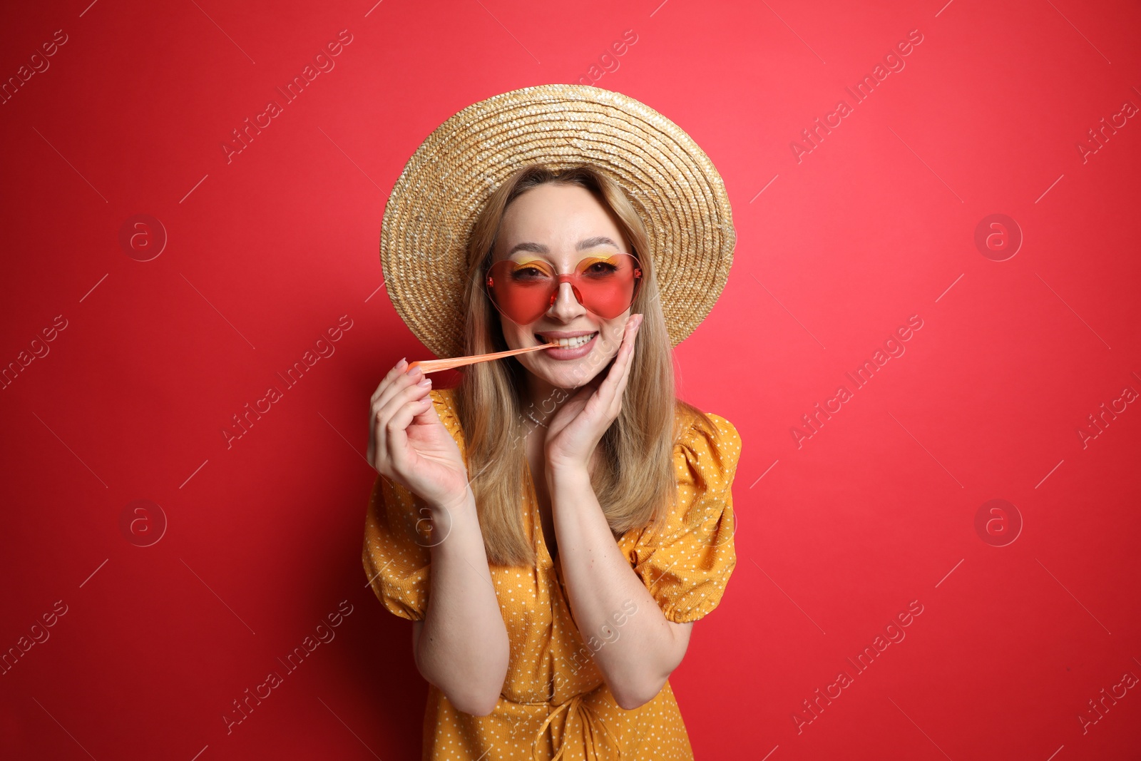 Photo of Fashionable young woman chewing bubblegum on red background