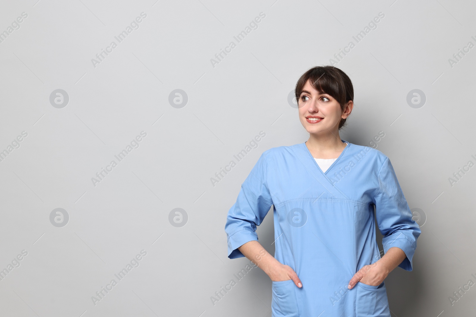 Photo of Portrait of smiling medical assistant on grey background. Space for text