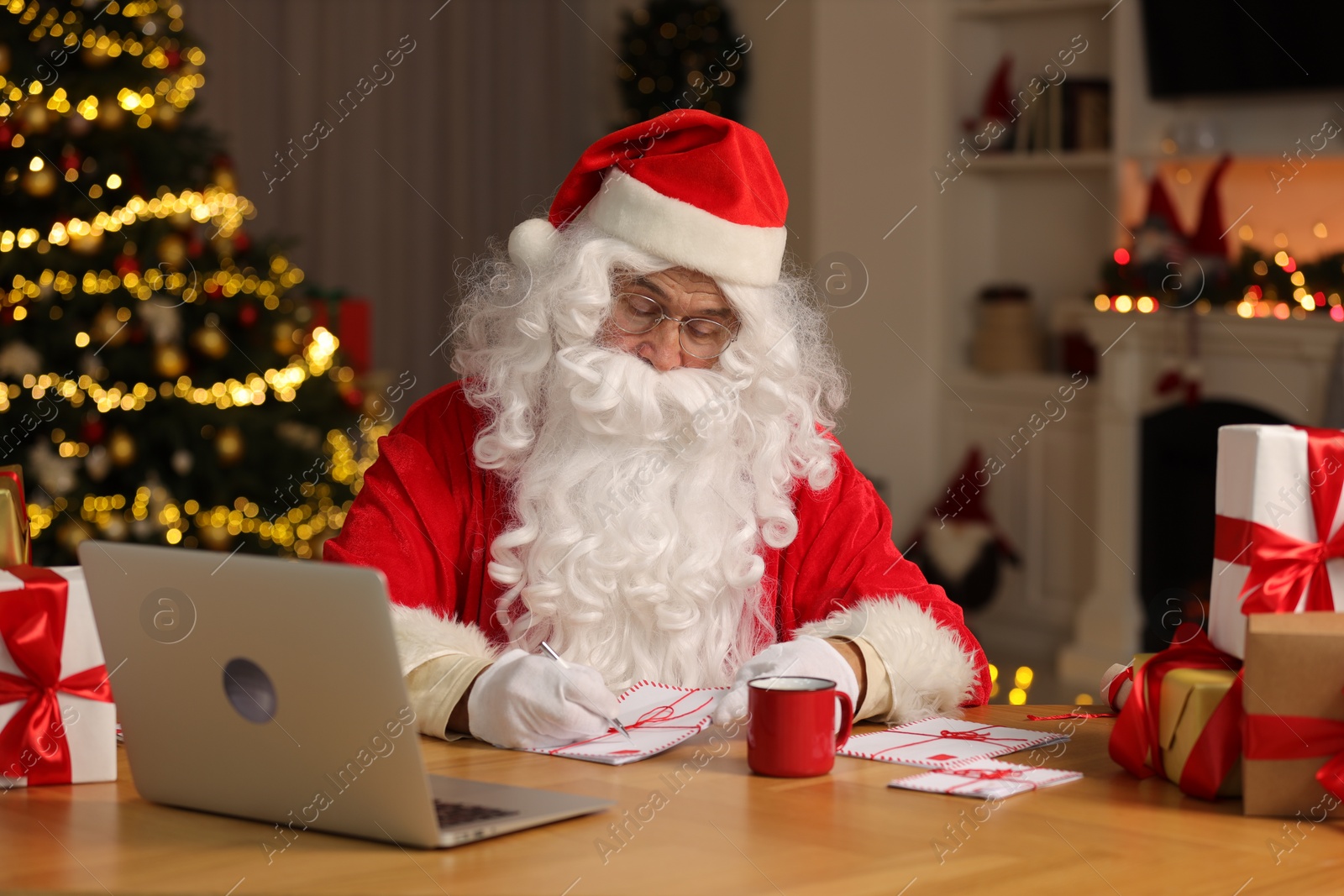 Photo of Santa Claus signing Christmas letters at table in room