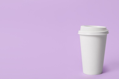 Takeaway paper coffee cup on violet background. Space for text